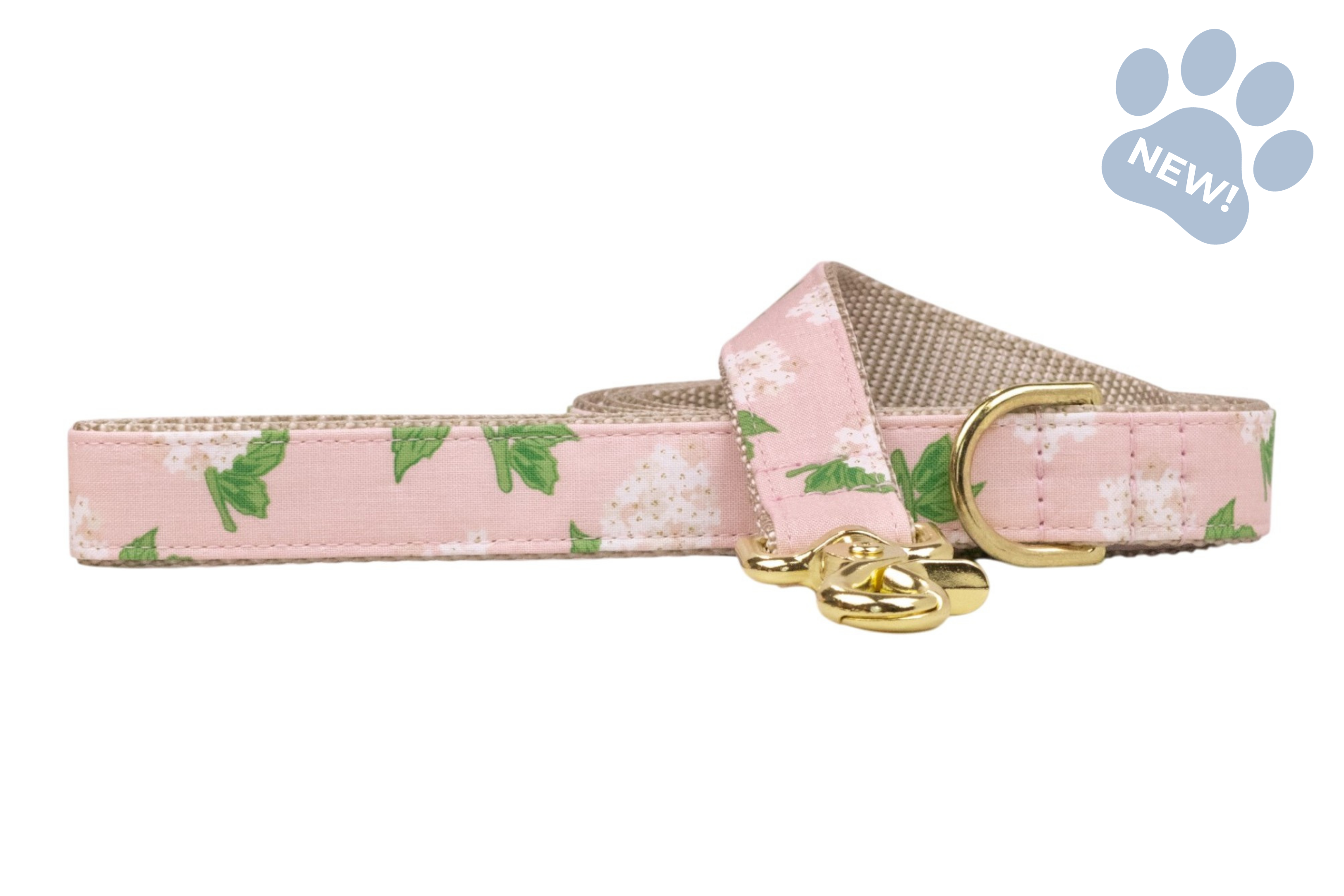 Hydrangea-print dog leash featuring a blush pink background with white hydrangea blooms and green leaves, accented by beige webbing and gold-tone hardware.