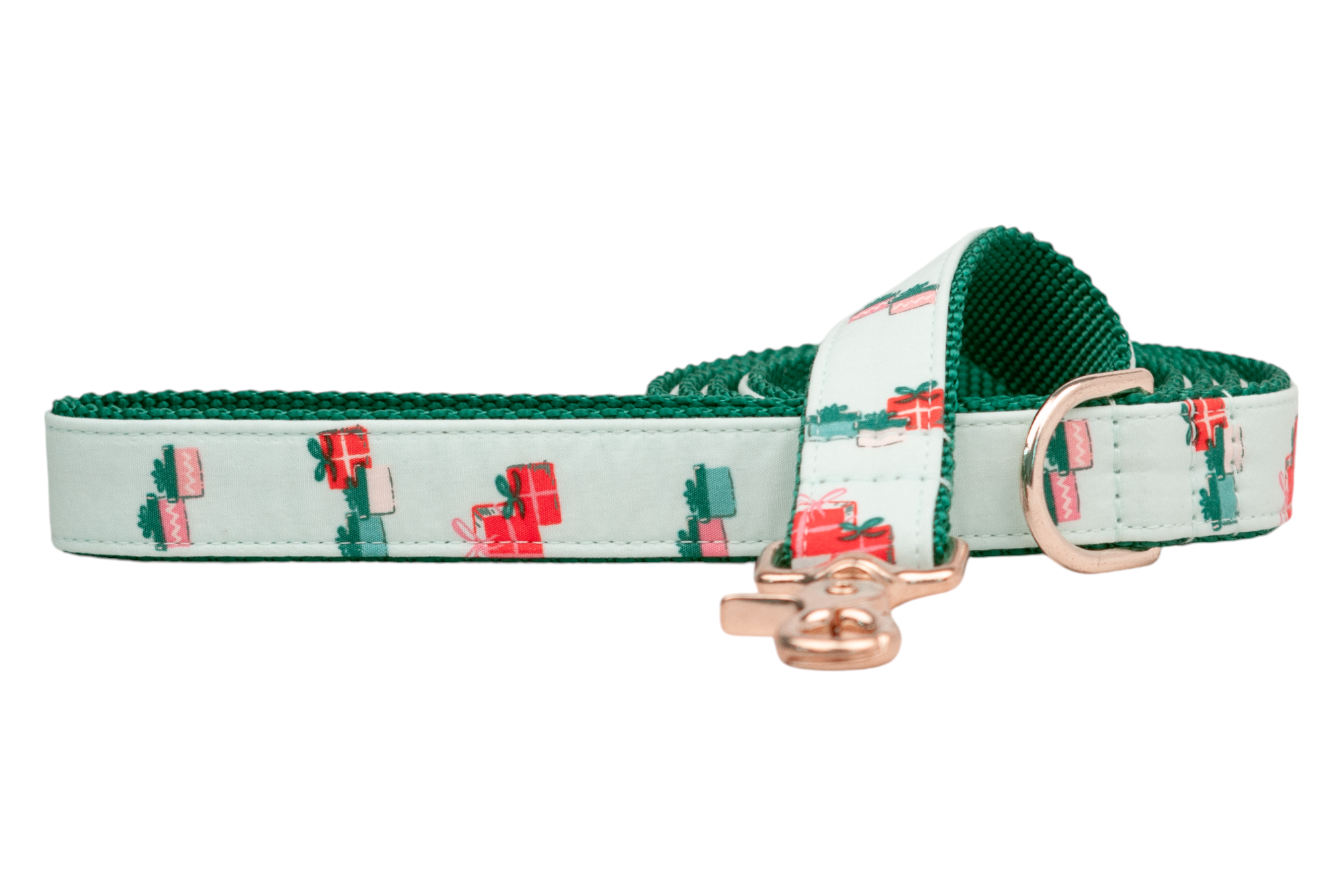 Holiday-themed dog leash with a soft green background adorned with neatly wrapped gift illustrations in festive tones. The leash is reinforced with durable green webbing and includes shiny gold hardware including a clip and a D-ring.