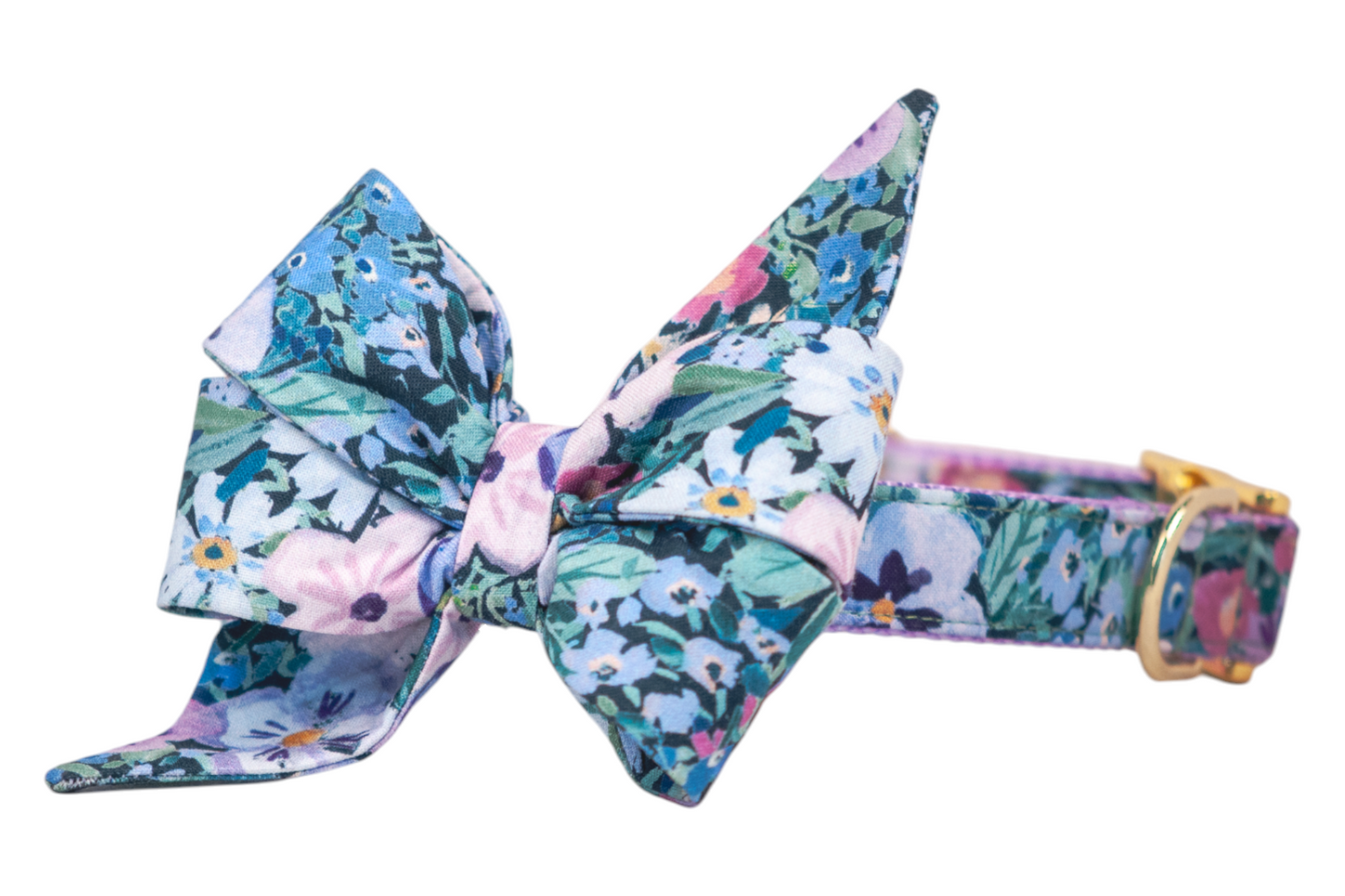A floral dog collar with a large, structured belle bow made from soft fabric featuring watercolor-style flowers in purple pastel tones. The belle bow has pleated loops and pointed tails, the collar includes lavender lining and metal hardware.