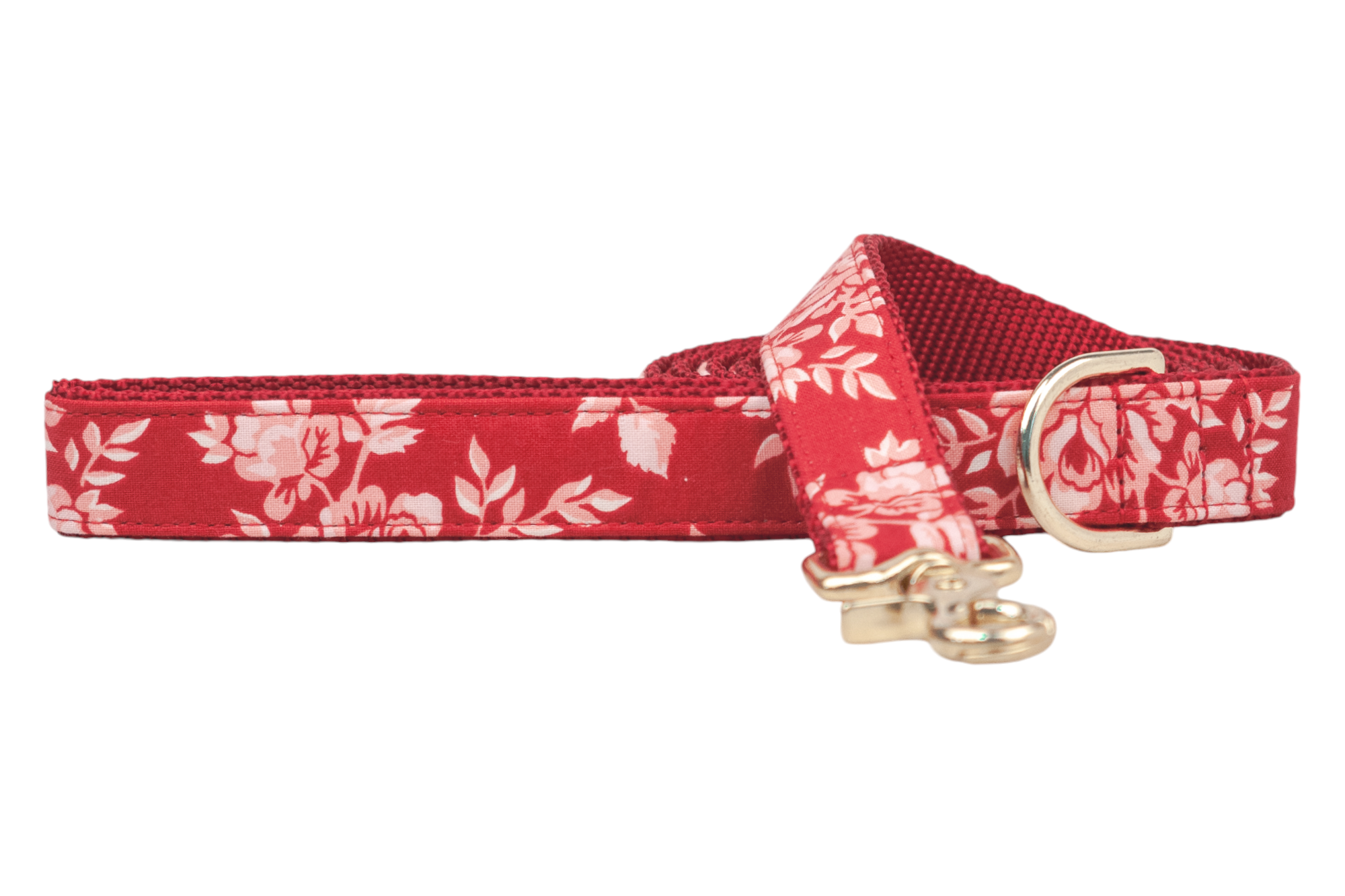 A red floral dog leash with a rose and leaf pattern, backed with durable red webbing. The leash features a metal clasp and a matching D-ring near the handle for added convenience. Handmade in Charleston, SC.