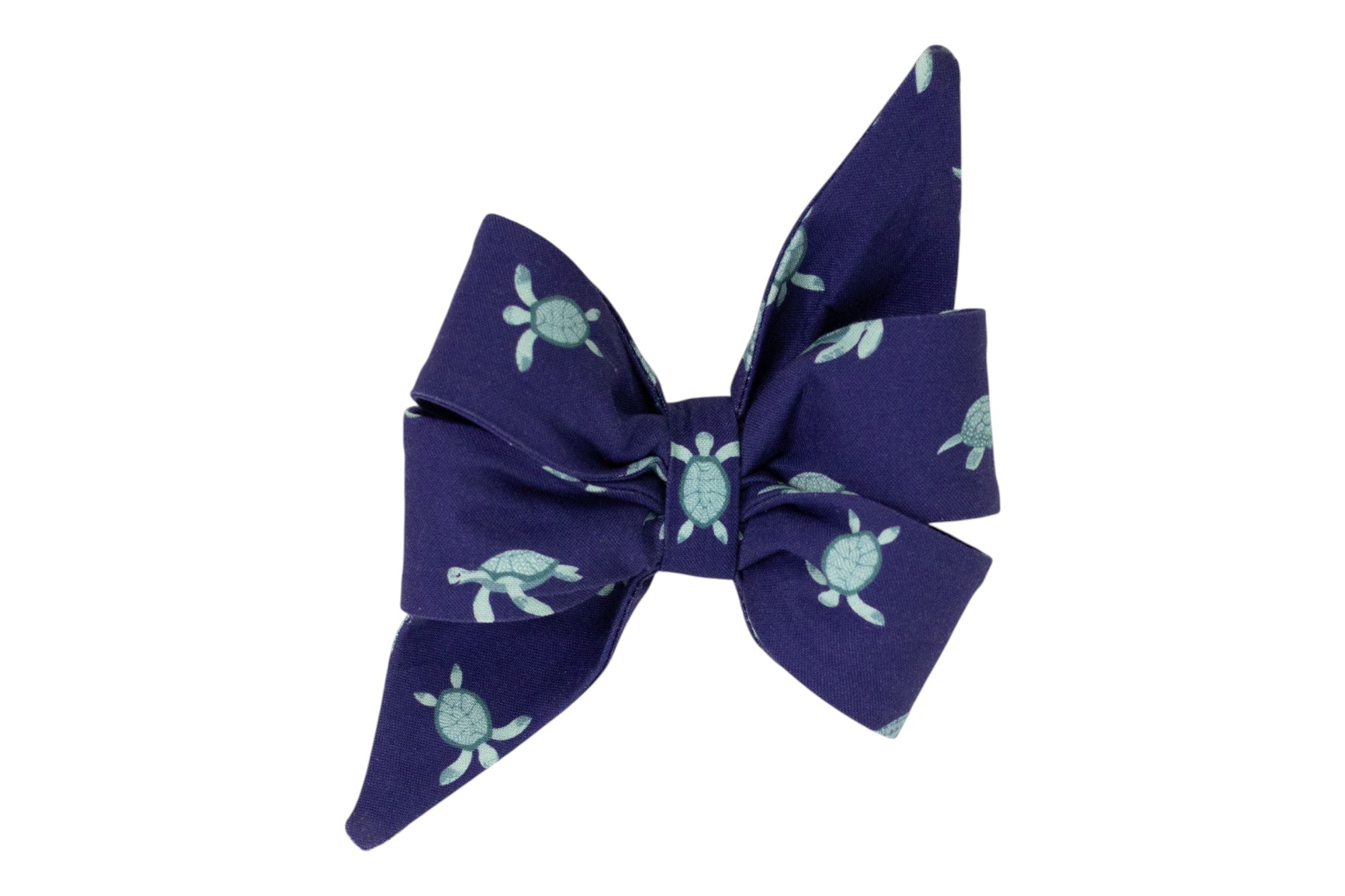 A deep navy fabric girl dog belle bow decorated with a light turquoise sea turtle pattern. The turtles are illustrated in a swimming pose, scattered evenly across the fabric.