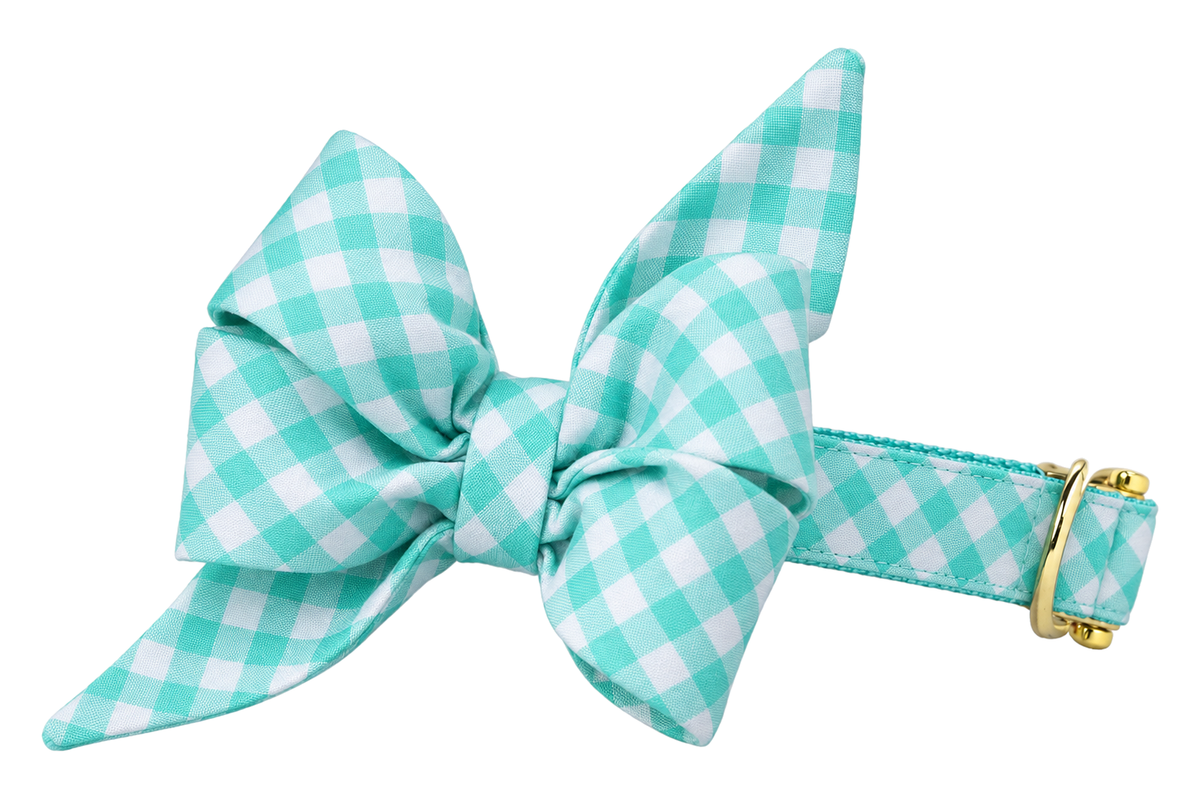 Dog collar featuring a large belle bow in Seafoam Picnic Plaid fabric, a crisp seafoam turquoise and white gingham check, attached to a matching Seafoam Picnic Plaid collar with a nylon inner lining and gleaming gold hardware, including a D-ring and buckle.