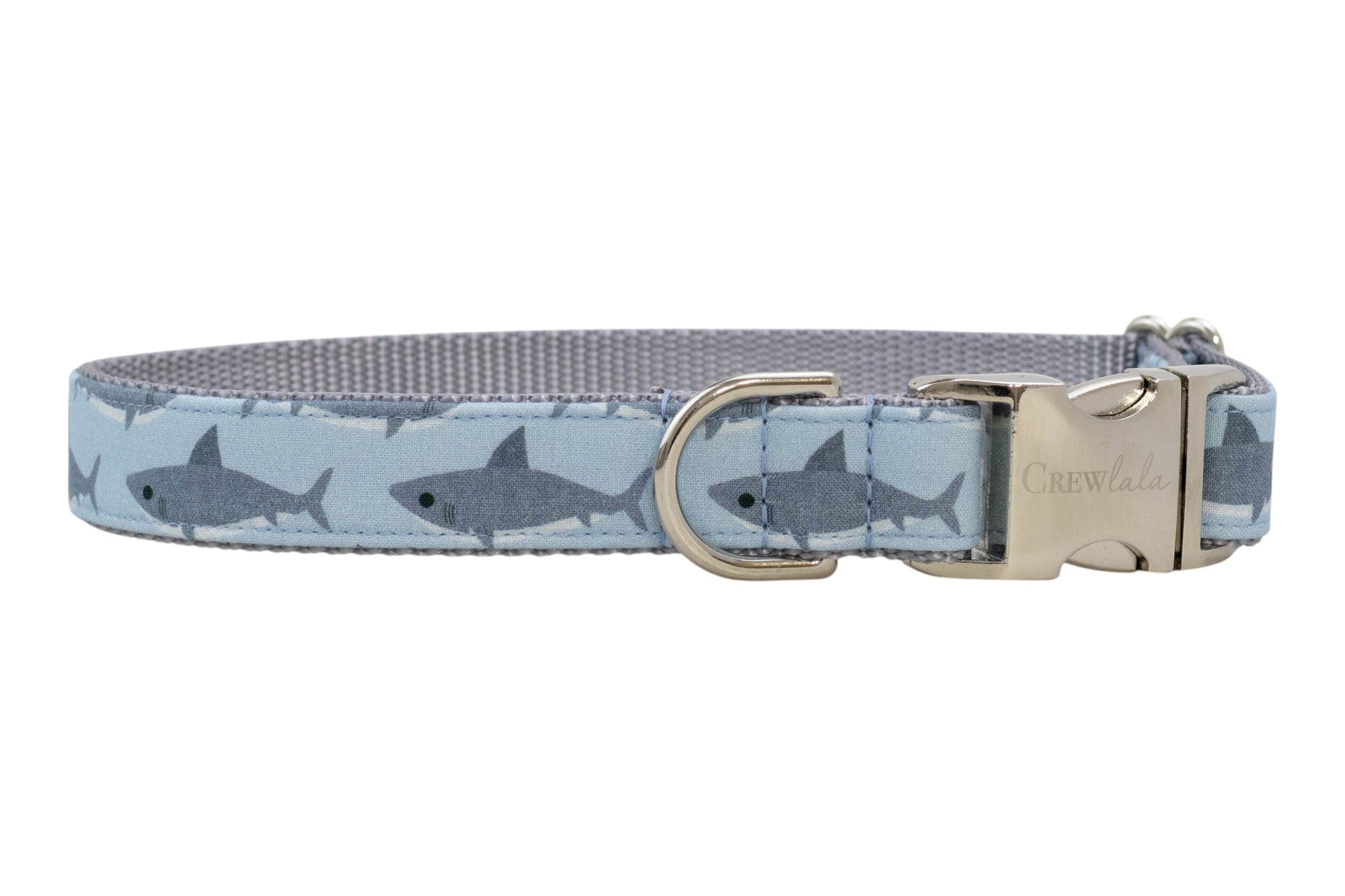 Light blue dog collar with a repeating gray shark pattern, featuring a silver buckle and metal D-ring.
