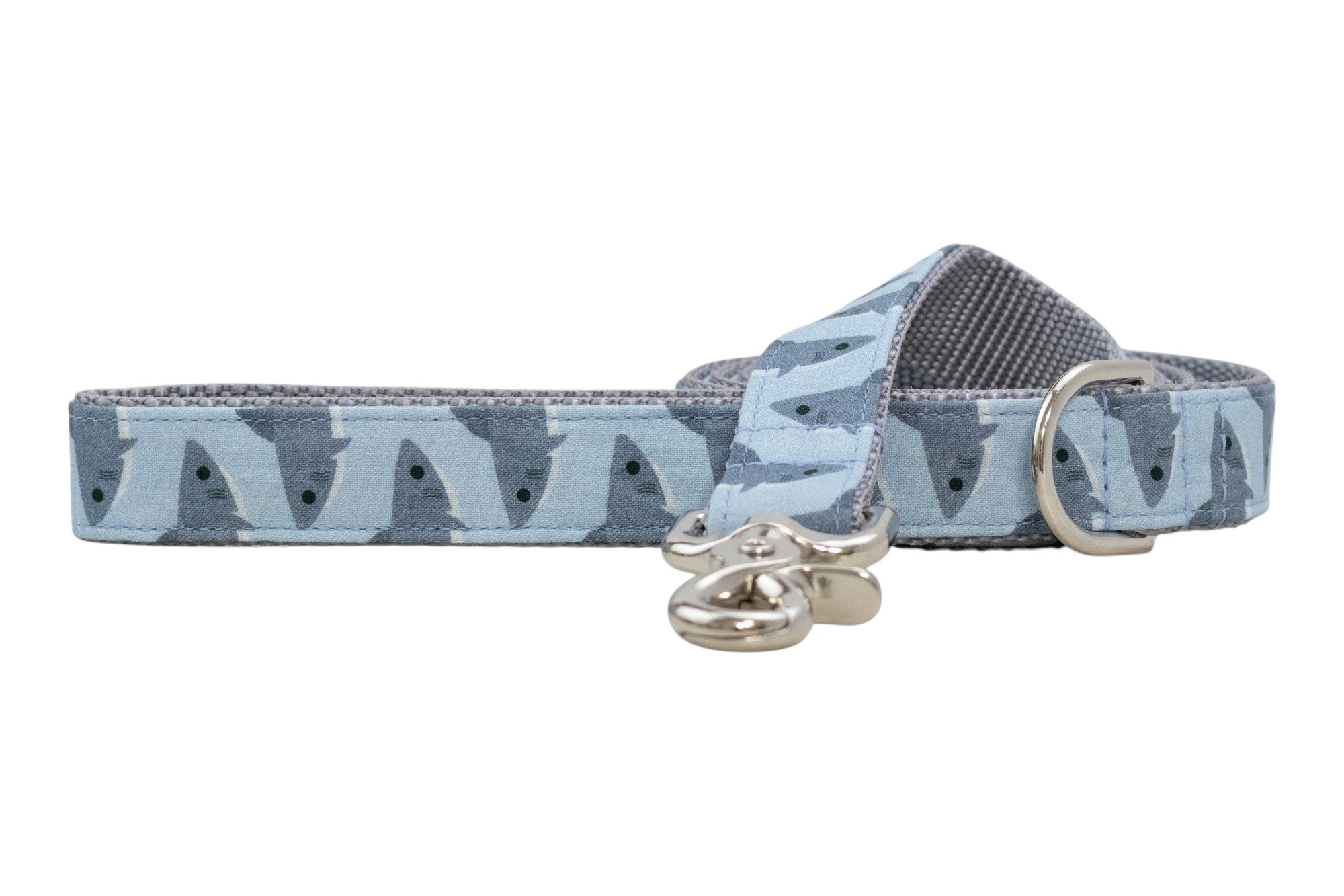 Light blue dog leash with repeating shark pattern and gray padded underside, featuring a silver clasp and D-ring.