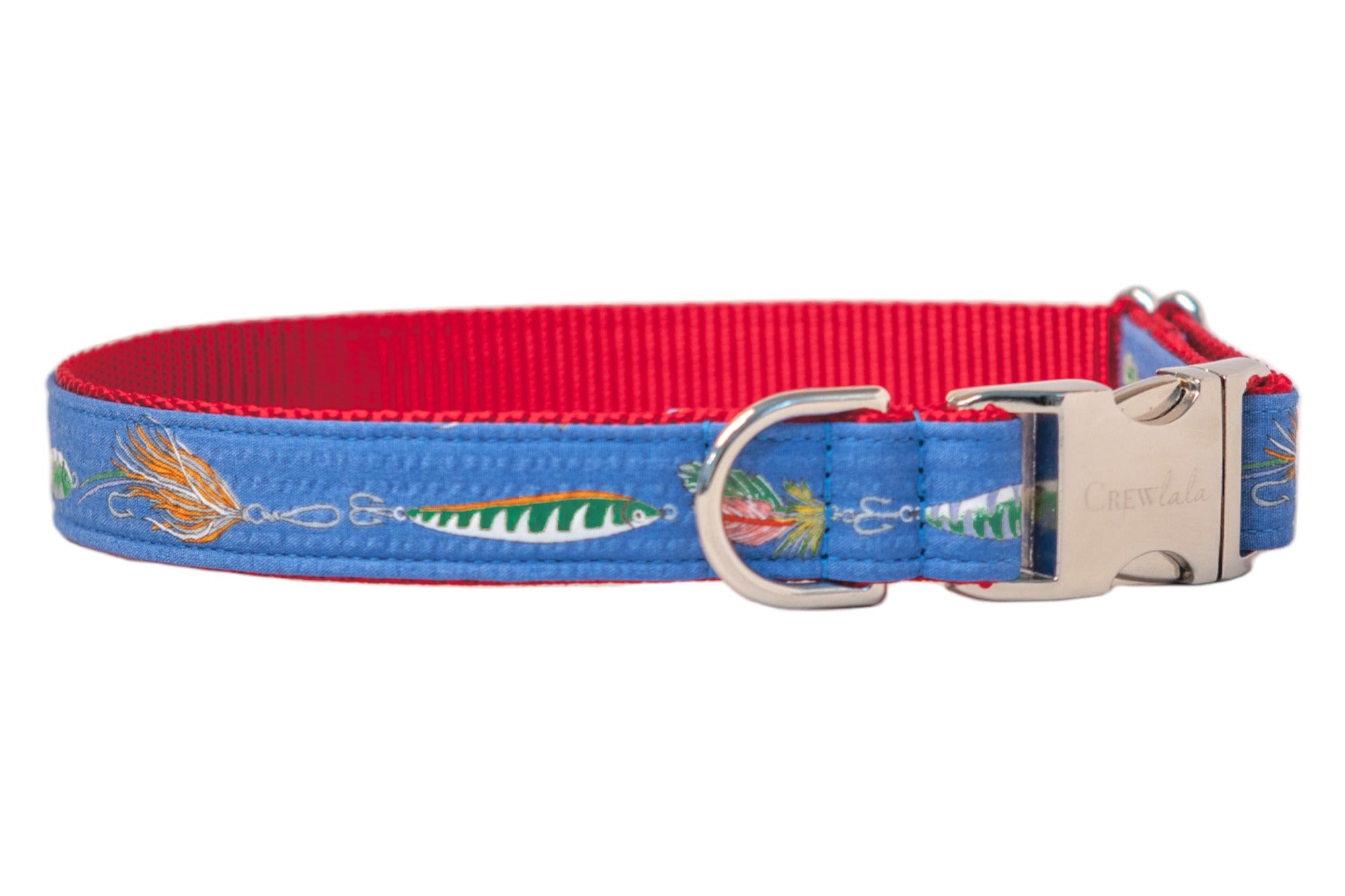 A close-up of a blue dog collar with a red interior featuring a playful fishing lure print, including hooks, feathers, and striped bait. The collar is finished with a shiny silver side-release buckle engraved with "CrewLala" and a sturdy D-ring for leash attachment.