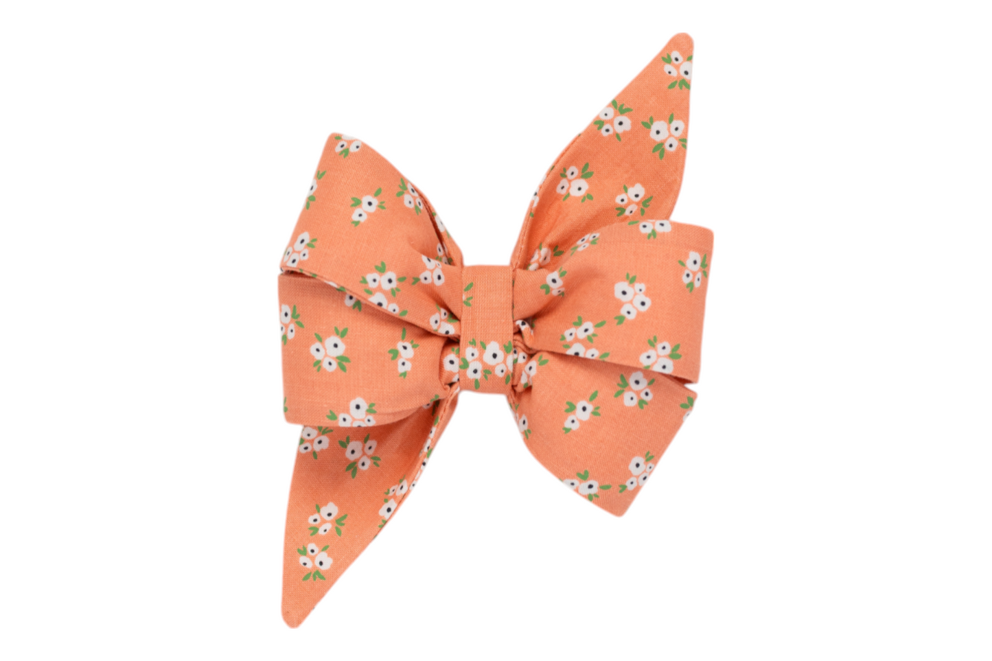 Handmade girl dog belle bow in a warm coral-orange color, adorned with a scattered pattern of small white flowers with green leaves.