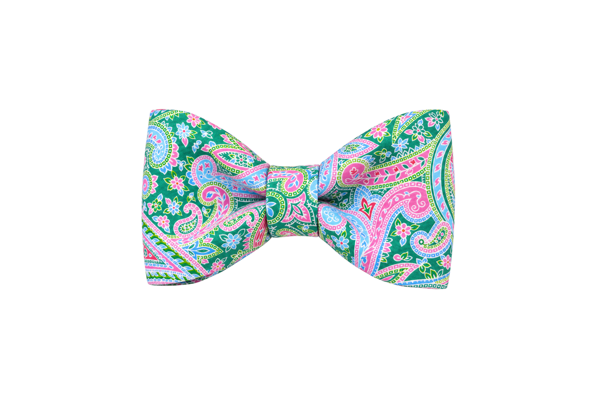 Classic dog bow tie in Vera Paisley fabric, a green, sky blue, pink and lavender paisley print, with a matching fabric center knot, photographed on a white studio background.