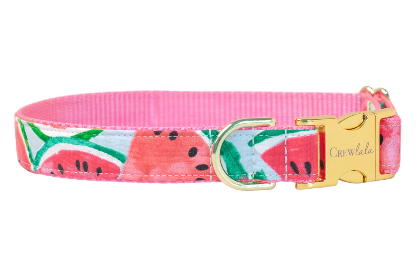 A dog collar featuring a bright watermelon slice print with red-pink fruit, green-striped rinds, and black seeds on a light blue background. The collar is lined with a pink woven interior and finished with gold-tone hardware, including a D-ring and a buckle engraved with the brand name “Crewlala.”