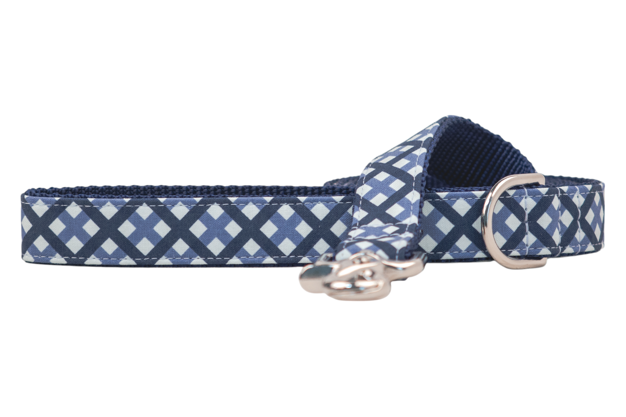 A close-up of a fabric dog leash with a navy blue and light blue plaid pattern on the outside and a textured dark blue inner webbing lining. The leash features reinforced stitching, a shiny metal D-ring, and a swivel clasp for attaching a leash.