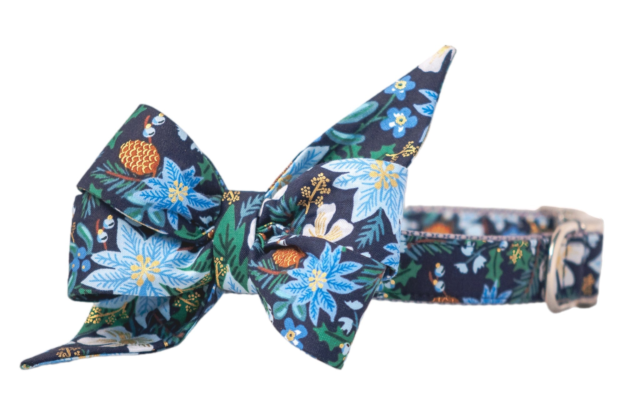 A festive dog collar with an oversized, pointed belle bow made from navy blue fabric. The design features a vibrant winter pattern with icy blue poinsettias, pale flowers, pinecones, foliage, and metallic detailing. The collar is adjustable with a metal buckle.