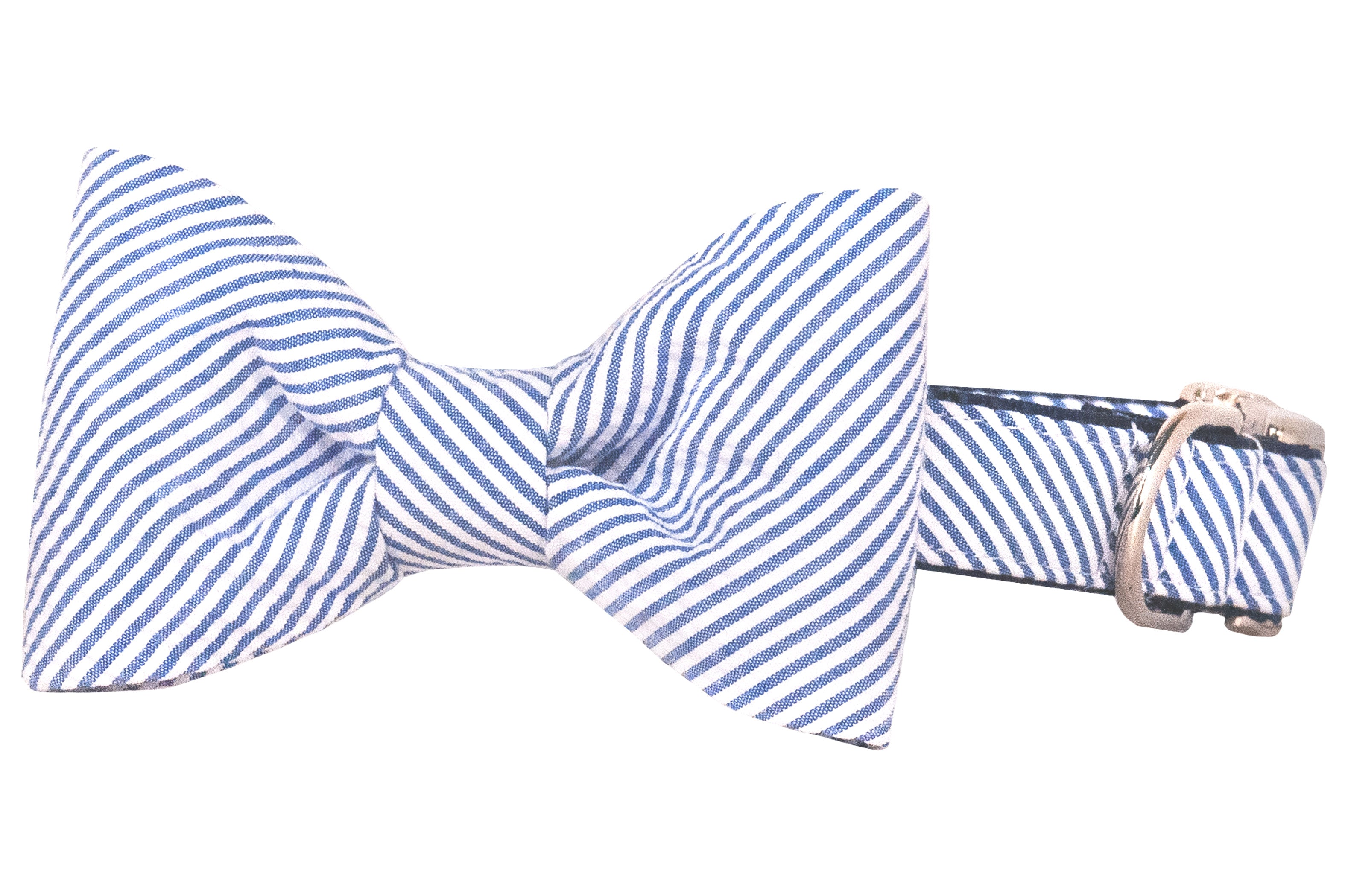 A blue and white diagonal striped dog collar with an attached bow tie made of the same seersucker fabric. The bow tie is neatly gathered at the center, creating a classic symmetrical shape with softly curved edges. The collar features a matching striped pattern and is equipped with a silver metal buckle and D-ring for leash attachment. The design has a polished, preppy look, combining charm with everyday functionality.