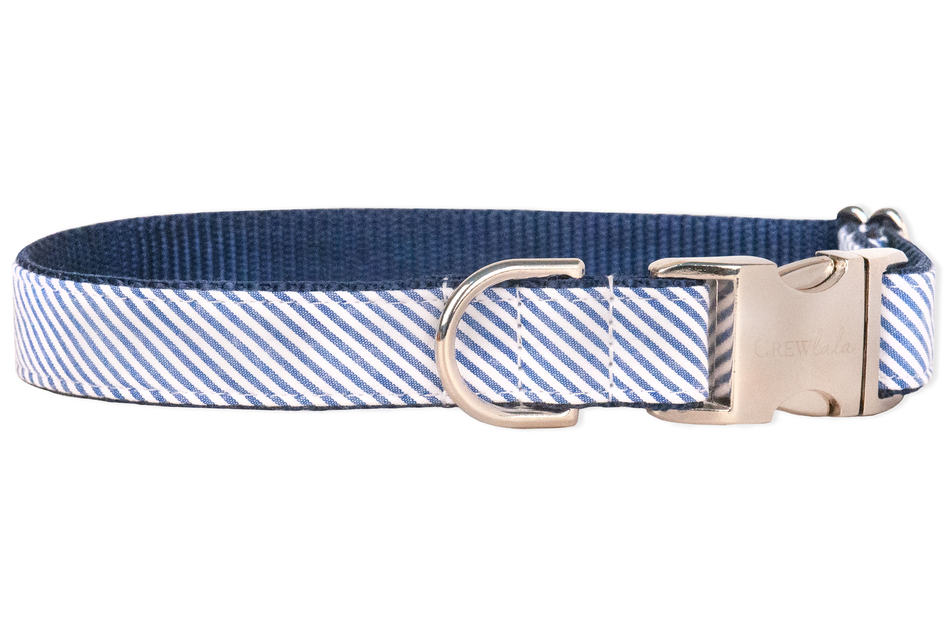A blue and white seersucker dog collar with a clean, nautical style. The exterior fabric features narrow stripes, while the interior is lined with durable navy nylon webbing. The collar includes a silver metal D-ring for leash attachment and a sturdy side-release buckle engraved with the brand name “Crew LaLa.” The stitching is precise, with reinforced sections near the hardware for added strength and durability.