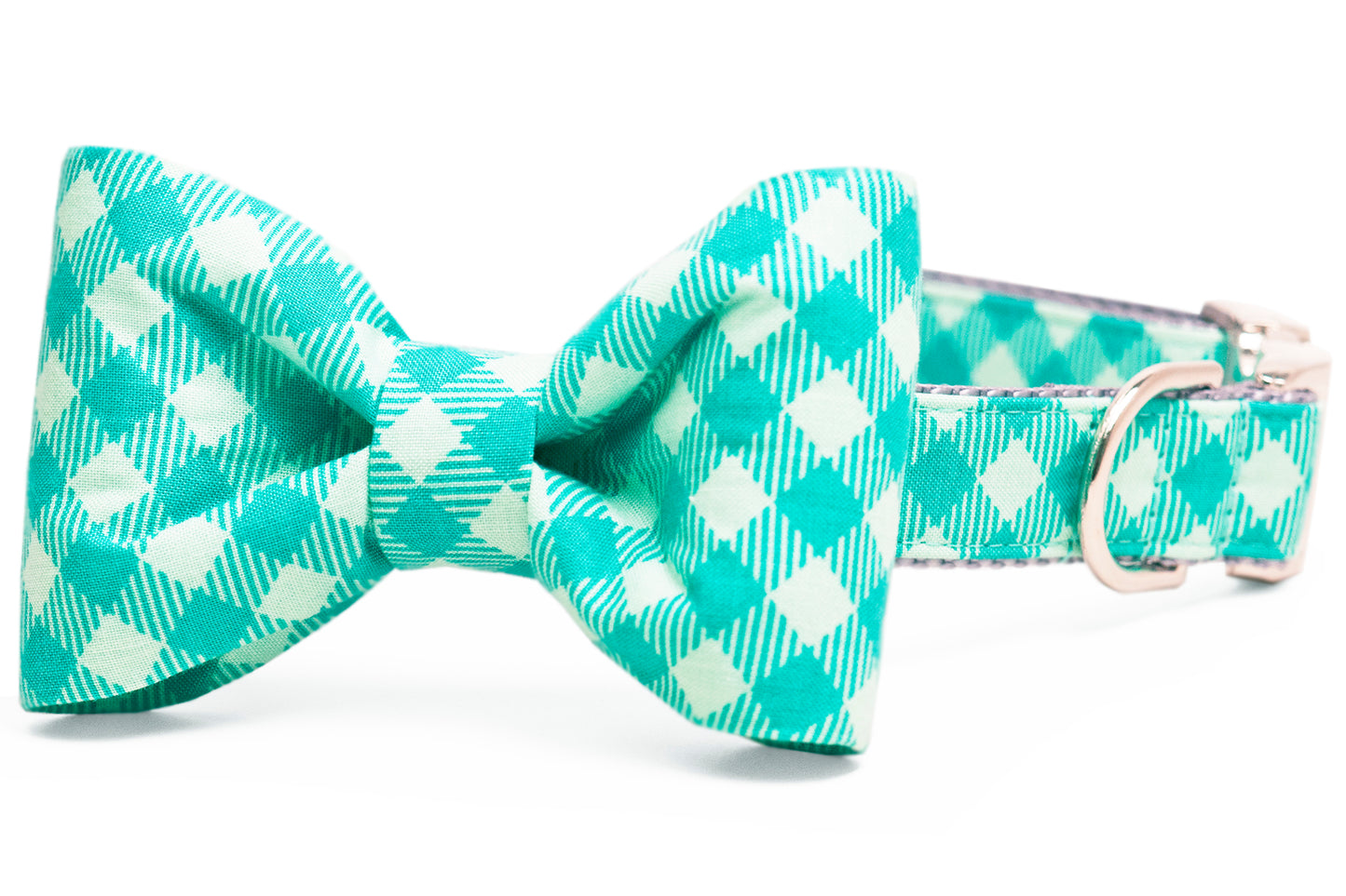 Close-up of a dog bow tie collar in a cheerful green plaid design. The structured bow tie displays crisp folds and a central knot, attached to the matching collar with a metal D-ring and clasp.