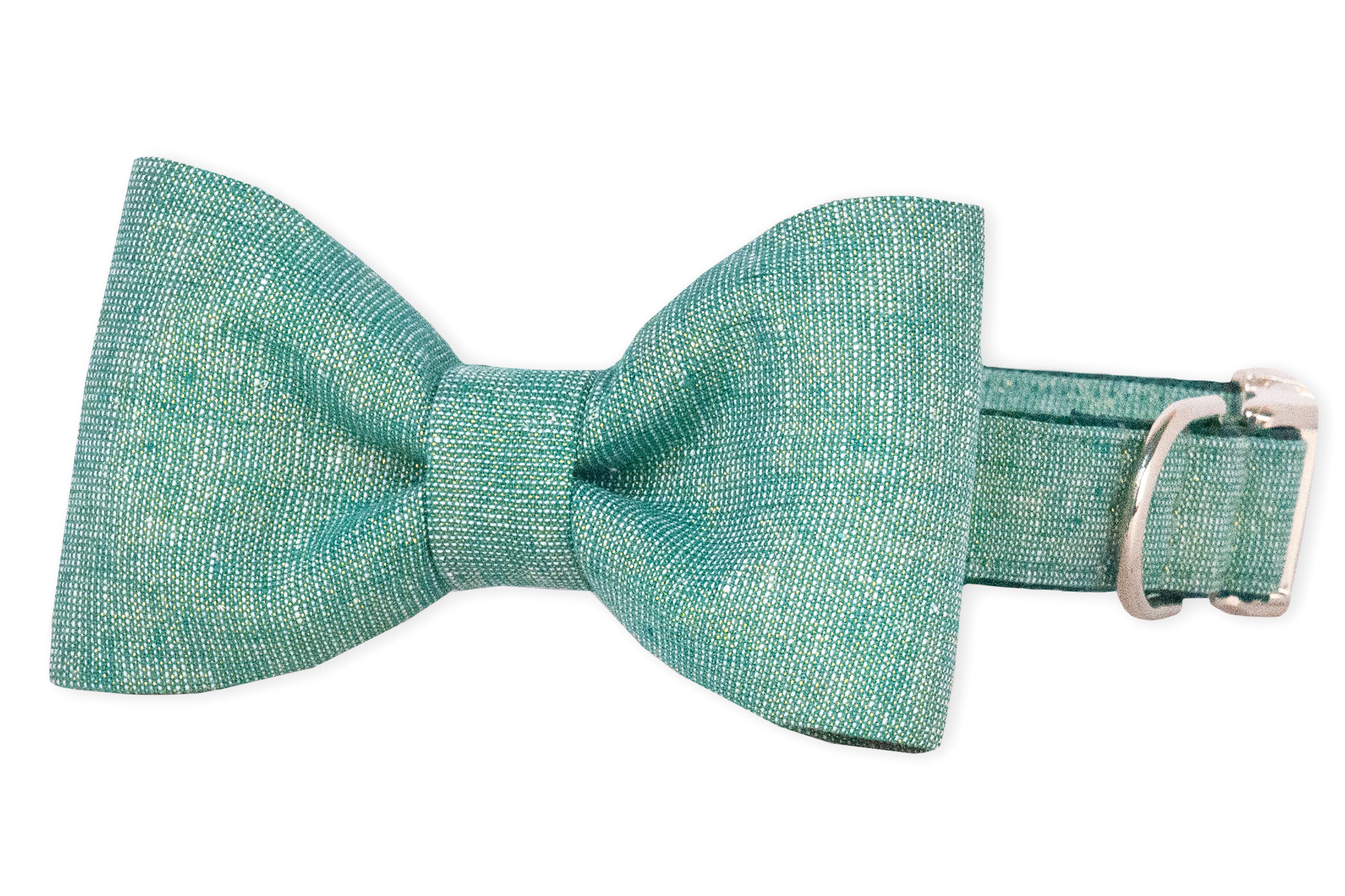 A green dog collar featuring an attached bow tie made of textured, speckled fabric. The matching bow tie is symmetrical and neatly structured, paired with metal hardware, including a rectangular buckle and adjustment slider.