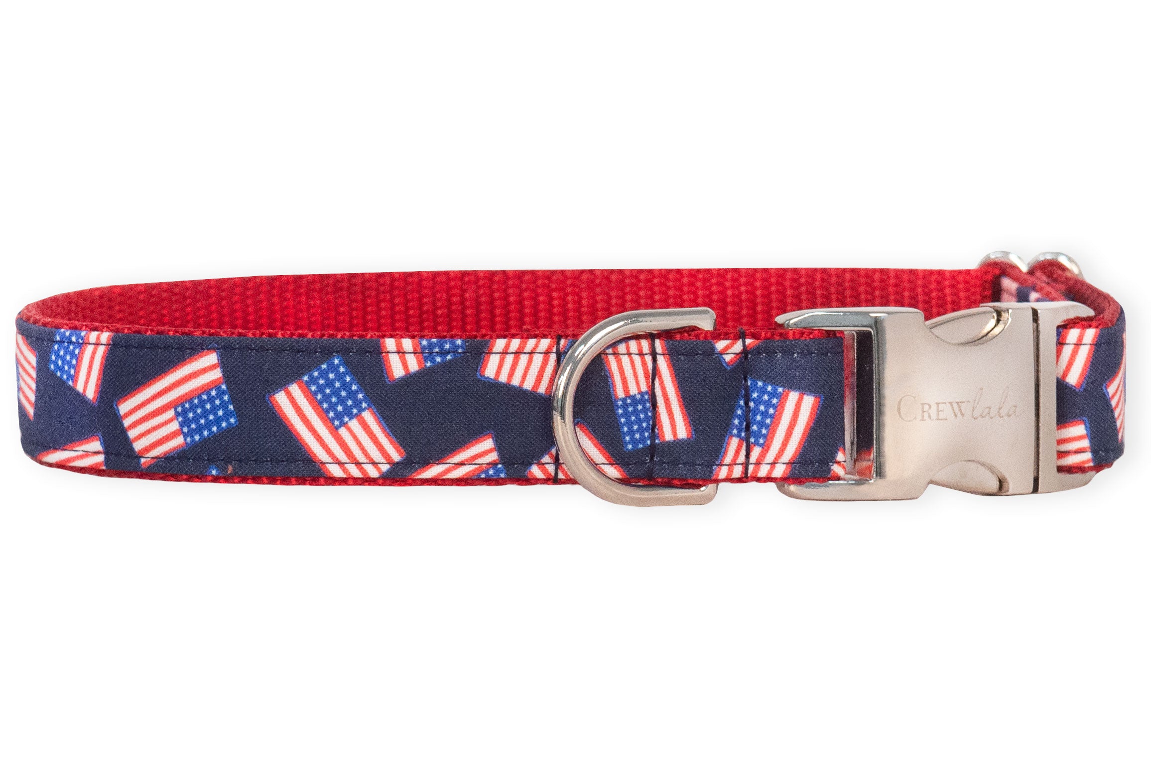 Adjustable dog collar with a navy blue fabric overlay featuring a repeating pattern of American flags. The collar is backed with vibrant red nylon and includes a polished silver metal buckle engraved with the brand name "Crew LaLa" alongside a matching silver D-ring for attaching tags or a leash.