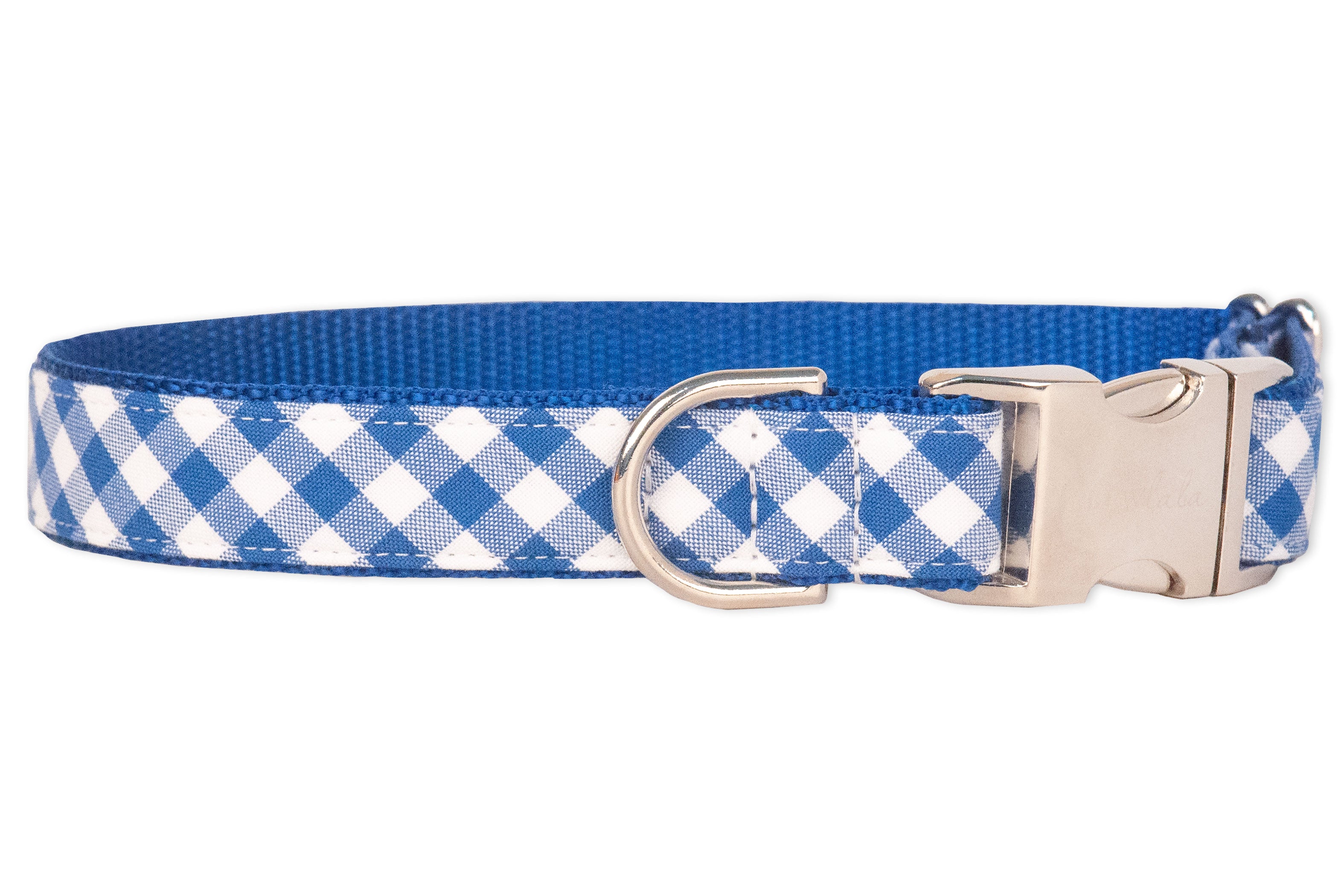 A dog collar with a classic blue and white plaid checkered pattern on the outer fabric and a solid blue woven nylon backing. The collar features silver-tone hardware, including a side-release buckle and a D-ring for leash attachment, combining style with durability.