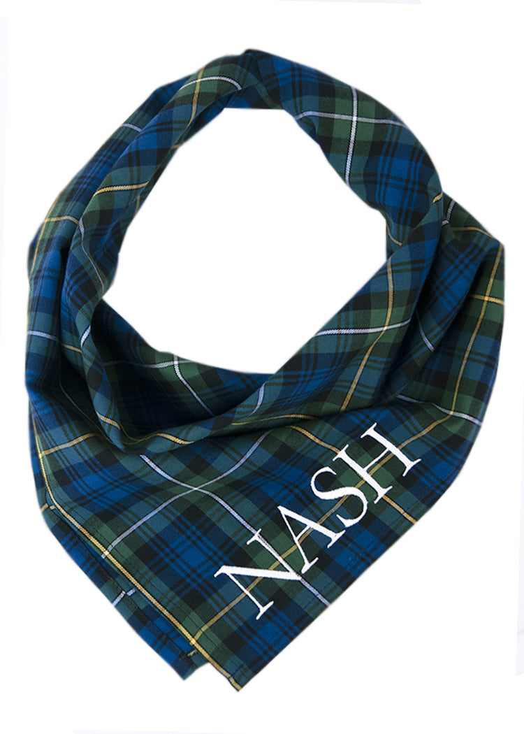 A classic green and navy tartan plaid dog bandana with light accents, shown with the name “Nash” embroidered for a personalized touch.