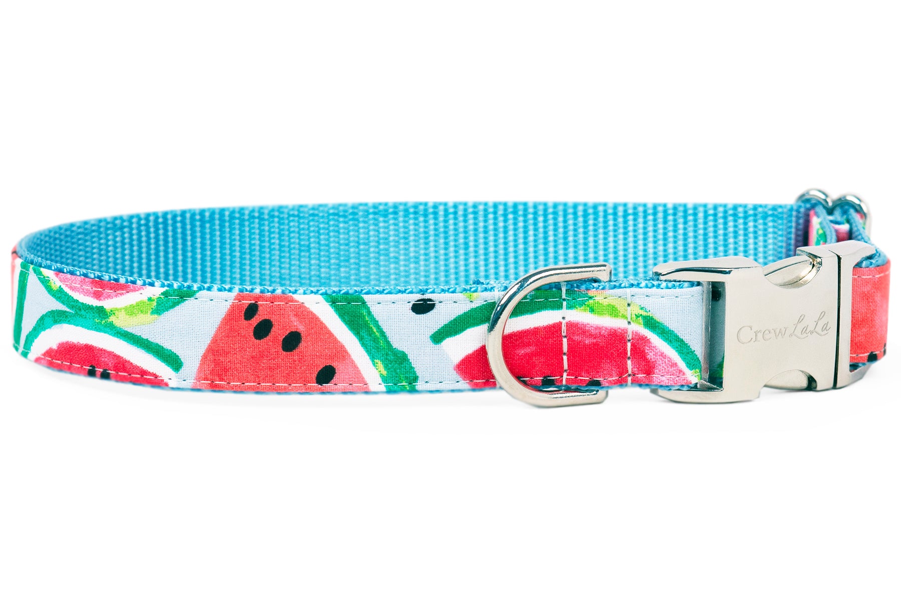 A dog collar featuring a bright watermelon slice print with red-pink fruit, green-striped rinds, and black seeds on a light blue background. The collar is lined with a blue woven interior and finished with silver-tone hardware, including a D-ring and a buckle engraved with the brand name “Crewlala.”