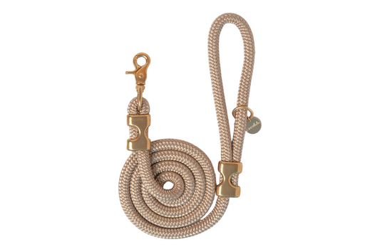 Durable gold rope dog leash made from tightly braided nylon with subtle sheen. Features polished gold-tone metal hardware, including a sturdy swivel snap hook, decorative clamps, and a round “Crew Lala” charm near the loop handle. The leash is coiled in a neat spiral for display.