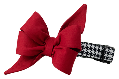 A stylish dog collar featuring a bold black and white houndstooth fabric overlay and an attached feminine red belle bow. The belle bow is made from structured cotton with crisp, voluminous loops and sharply pointed tails, creating a dramatic and elegant silhouette. The collar includes black metal hardware and an adjustable strap, combining classic sophistication with playful charm—ideal for formal events, game day, holiday photos, or seasonal wear.