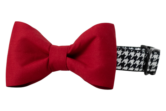 A black and white houndstooth-patterned dog collar with a bold, attached red bow tie. The collar features a classic, adjustable design with black hardware, while the classic bow tie adds a striking, formal touch—ideal for holiday, game day, or special occasion wear.
