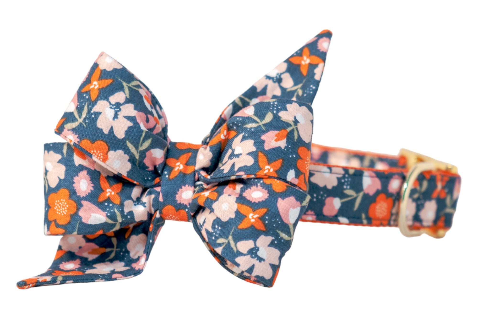 Dog collar adorned with an oversized four-loop belle bow in a vibrant floral print of blossoms with leafy stems on a dark blue background. The belle bow’s top loops are elongated and pointed, while the bottom loops are fuller and angled outward, giving it a feminine style. The matching collar is adjustable with metal hardware.
