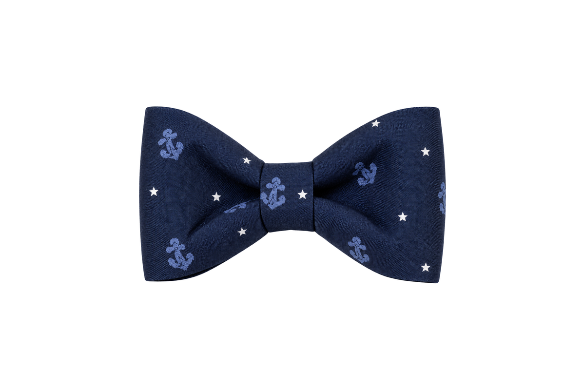 Classic dog bow tie in Anchors Away fabric, a navy blue fabric with small tonal periwinkle blue anchors and tiny white stars, with a matching fabric center knot, photographed on a white studio background.
