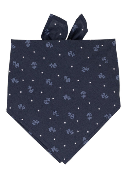 A navy blue nautical themed fabric bandana for dogs, decorated with a repeating pattern of light blue anchors and white stars, neatly folded with tied ends visible at the top.