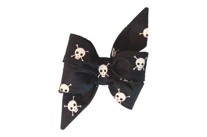 Bold and edgy girl dog belle bow with skull and crossbones pattern on a sleek black backdrop, perfect for the rebellious pup.