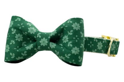 Green floral dog collar with a centered bow tie, crafted from matching fabric printed with pale green flowers and leaves. The bow tie has a crisp, symmetrical design, and the collar is fitted with shiny hardware, including an adjustable buckle.