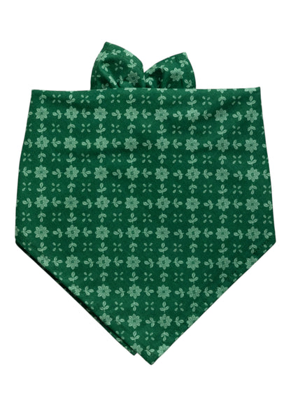 Dog bandana made from deep green fabric patterned with evenly spaced light green floral motifs. The floral design consists of daisy-like blooms arranged in neat vertical and horizontal rows. 