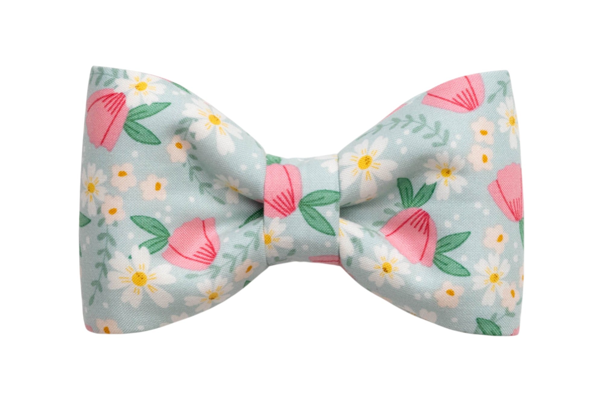 Floral dog bow tie with pink blossoms, white daisies, and green leaves on a pastel blue background for a fresh spring look.