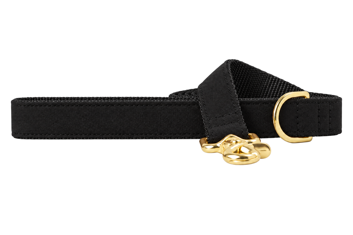 Black Tie Woven dog leash made with a solid black woven fabric with a subtle texture, lined with black nylon webbing, with a handle loop and a gold trigger clip.