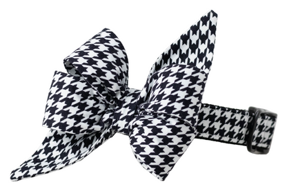 Chic dog collar in a bold black and white houndstooth print, featuring an attached large belle bow made of the same fabric. The belle bow has structured folds and long, pointed tails for a dramatic flair, and the collar includes matte black hardware and reinforced stitching—perfect for stylish pups at formal or seasonal events.