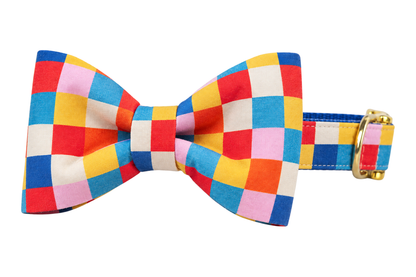 Classic dog collar featuring a Block Party fabric bow tie, a bold colorblock check of red, cobalt blue, yellow, orange, pink and cream squares, attached to a matching Block Party collar with a nylon inner lining and gleaming gold hardware, including a D-ring and buckle.