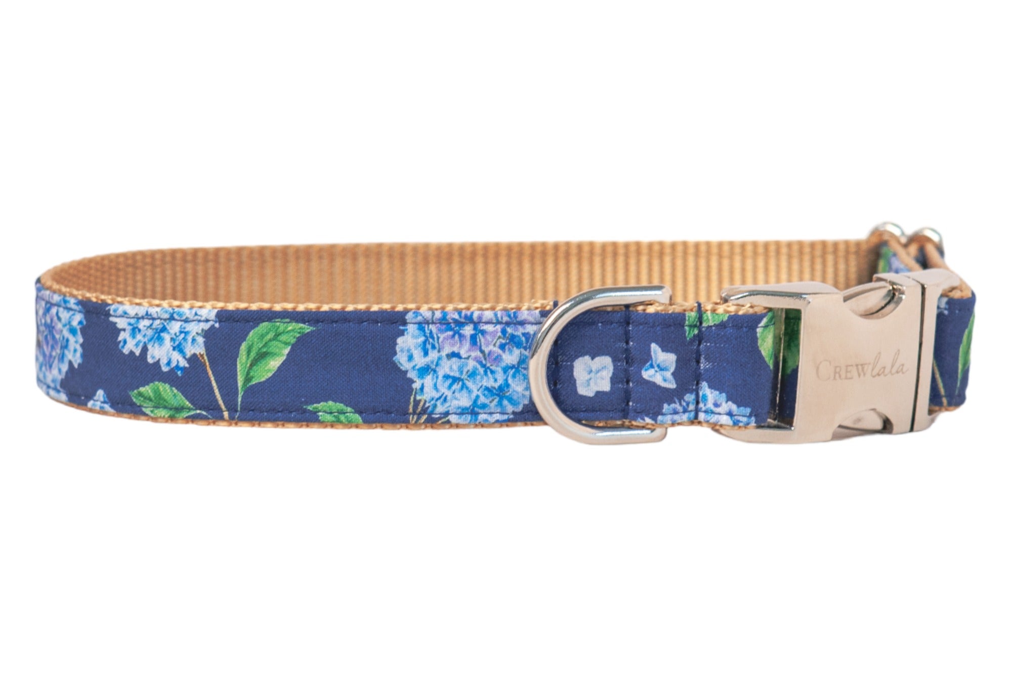 Dog collar with a navy blue fabric exterior featuring a floral print of blue hydrangeas and leaves. The collar has a woven backing and metal hardware, including a D-ring and a side-release buckle engraved with the brand name "Crewlala."