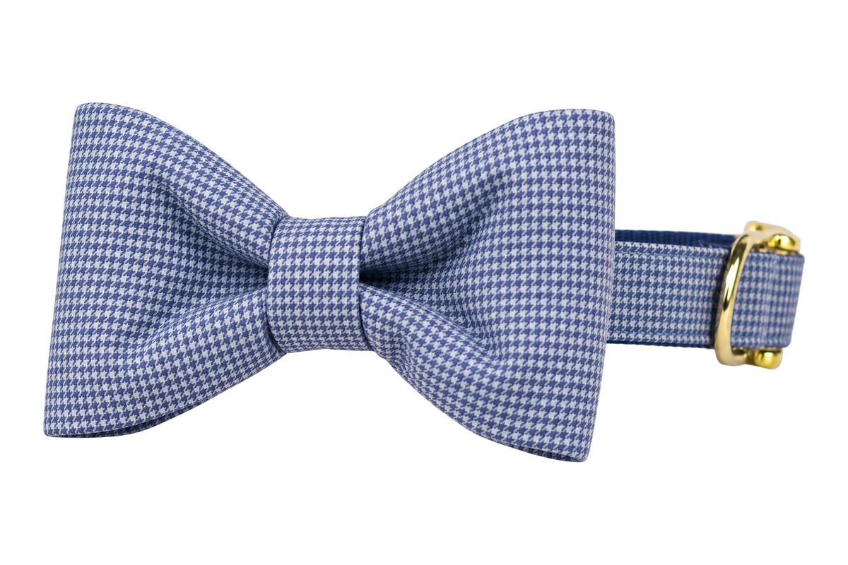 Classic dog collar featuring a Blue Houndstooth fabric bow tie, a fine periwinkle blue and white mini houndstooth check, attached to a matching Blue Houndstooth collar with a nylon inner lining and gleaming gold hardware, including a D-ring and buckle.