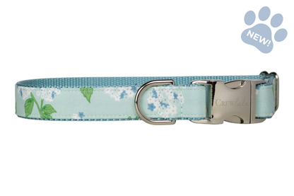 Adjustable dog collar featuring a soft mint blue background with white hydrangea blooms, blue floral accents, and green leaves, finished with silver-tone hardware and matching blue webbing.