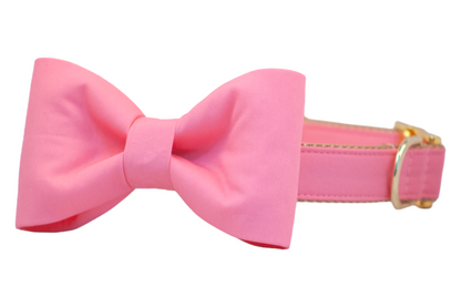 A stylish dog collar in bubblegum pink with a matching classic bow tie attached, tan woven interior, and polished gold-tone D-ring and buckle, designed for special occasions or everyday flair.