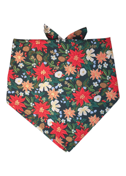 Holiday-themed dog bandana with a rich floral pattern that includes poinsettias, beautiful blossoms, pinecones, green sprigs, and scattered berries on a deep green background. The background enhances the festive tones, while the tie-back style offers an adjustable fit.