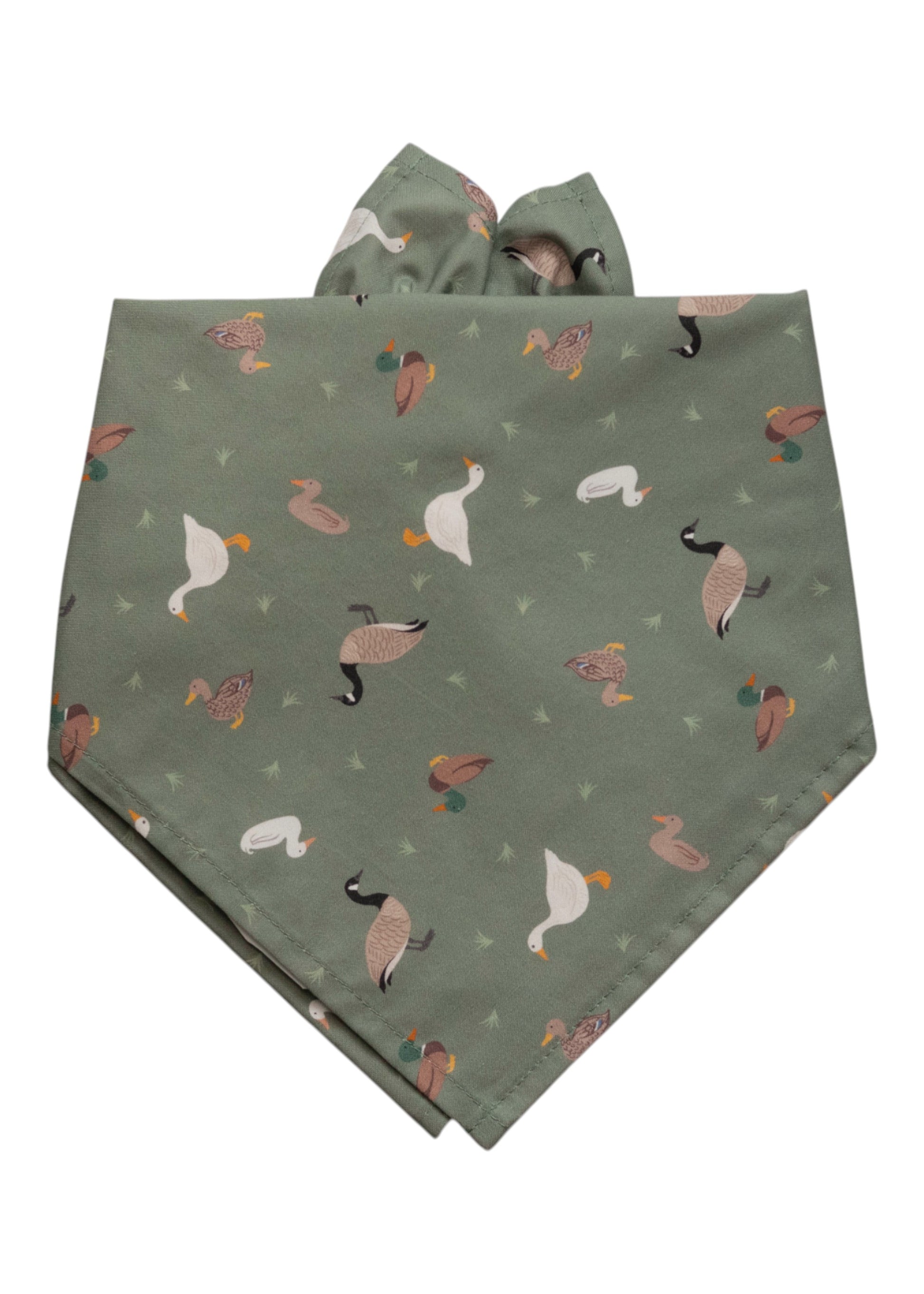 Sage green dog bandana with an all-over print of illustrated ducks, geese, and mallards, scattered with small green grass tuft accents.
