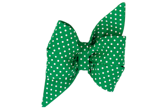 A bold feminine dog belle bow in bright green fabric with evenly spaced white polka dots. The oversized shape includes flared ends and a cinched center, giving it a cheerful, standout appearance for festive or fashionable wear.