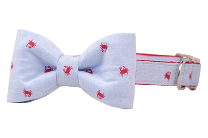 Nautical-themed dog bow tie and collar matching set in light blue, decorated with tiny red crabs. The collar features silver a silver d-ring and buckle.