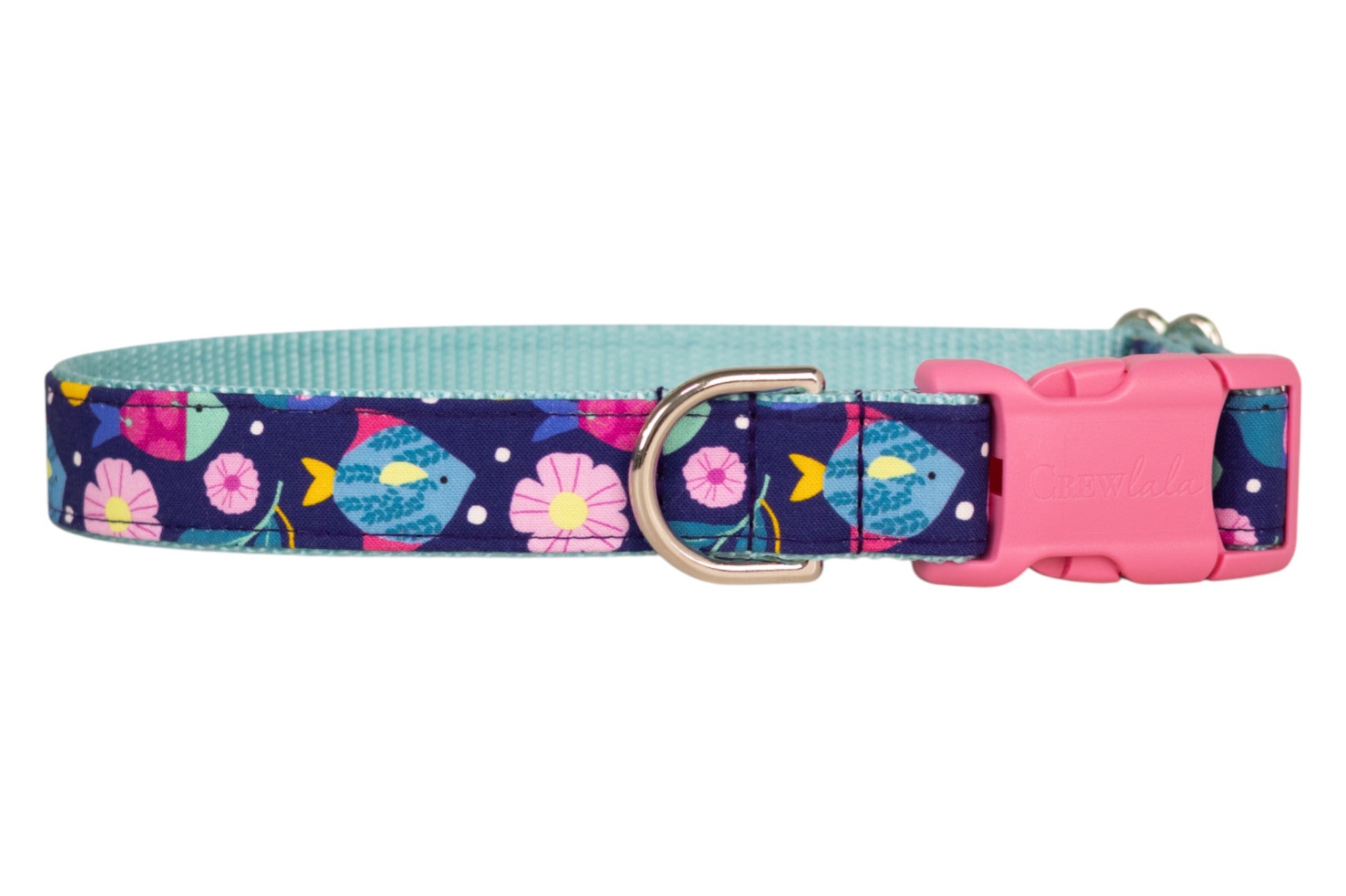 A navy blue dog collar with a colorful print of fish, flowers, and polka dots. The collar features a light blue woven inner lining, a silver metal D-ring, and a pink plastic buckle.