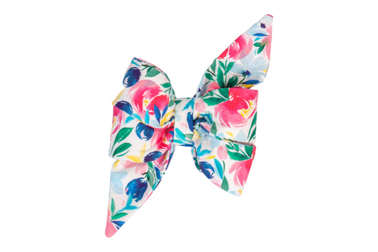 Floral feminine dog belle bow with a bright watercolor-inspired print in pinks, deep blues, and splashes of yellow and green. The oversized belle bow has sharply pointed tails and layered loops, held together at the center for a playful and polished pet accessory.