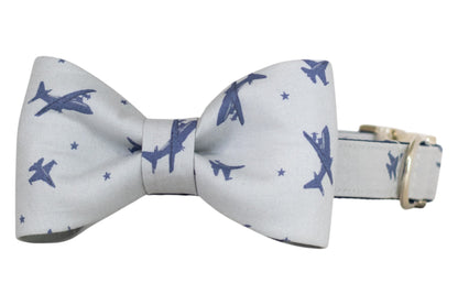 Aviation-themed gray bow tie featuring scattered navy blue jet silhouettes and small stars, secured to a matching dog collar with silver hardware.