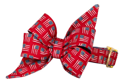  Patriotic-themed red belle bow for girl dogs, decorated with miniature American flag designs throughout, paired with a matching collar with a gold buckle. 