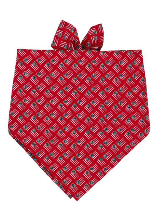 A red Patriotic bandana pet accessory decorated with a repeated pattern of American flags. The bandana is folded into a triangular shape.