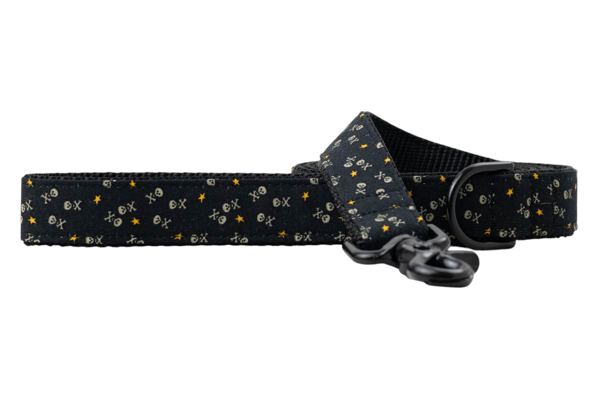 Black dog leash with a repeating pattern of small skull-and-crossbones, “X” marks, and stars, reinforced with black woven backing and featuring matte black metal hardware including a swivel clasp and D-ring.