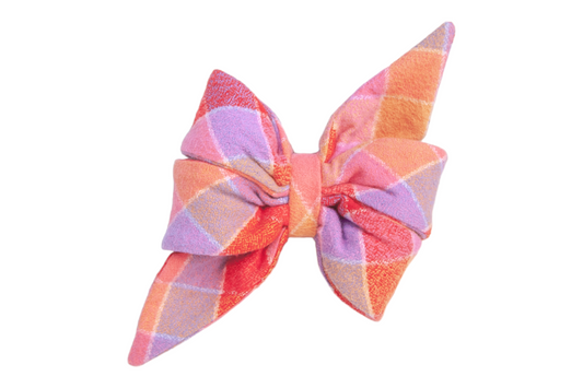 Flannel dog belle bow in a pointed, double-looped shape featuring a plaid pattern in warm hues. The soft, textured material has a subtle sheen, adding depth to the pastel and jewel-tone color scheme.